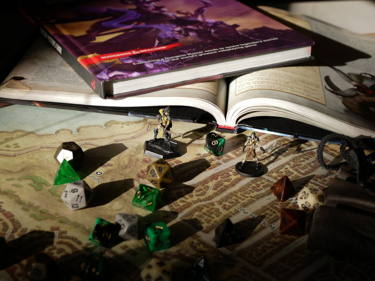 About Close-up of tabletop RPG setup with books, dice, and figurines on a map.
